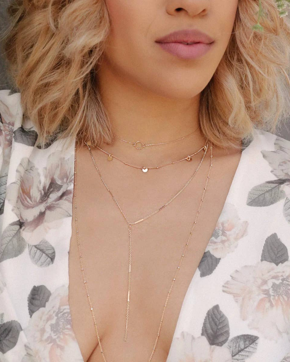 Gold filled ball chain necklace with five tiny disc charms layered on model