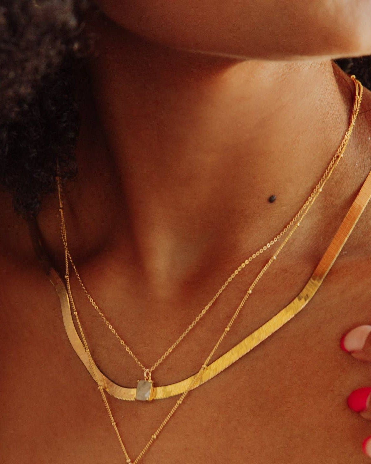 Gold layered necklaces with labradorite emerald pendant on model's neck