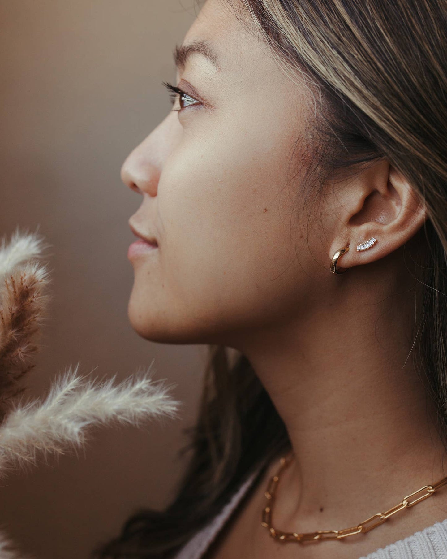 Solid 10k gold flat huggie hoop earrings worn on model's ear