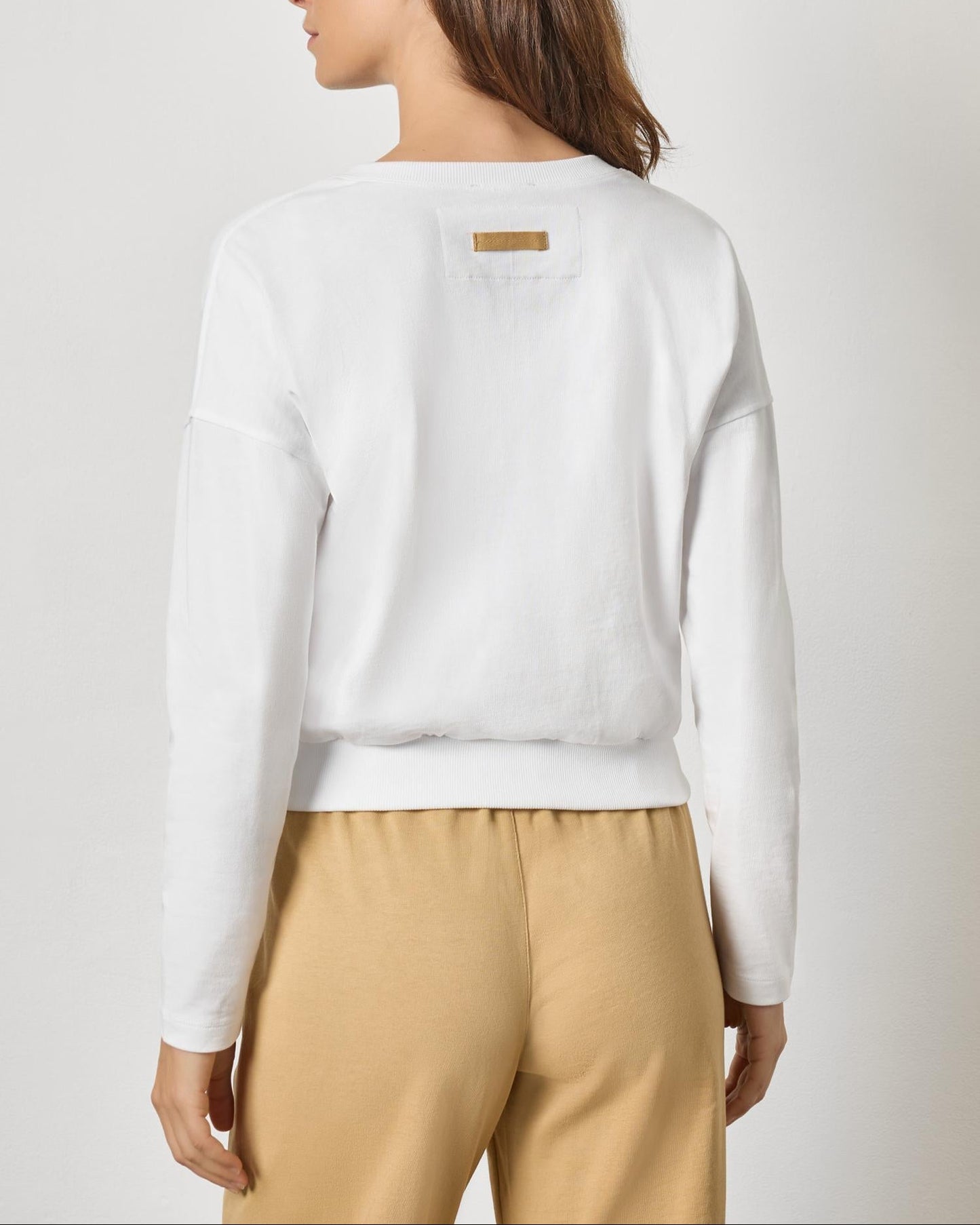 Back view of white rib trim cardigan with gold label detail on model