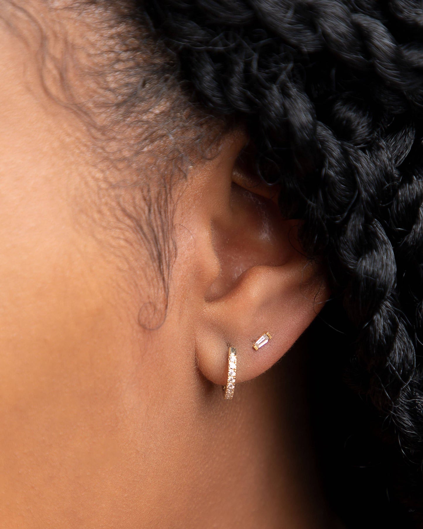 10k gold pave CZ huggie hoop earring worn with baguette stud on ear