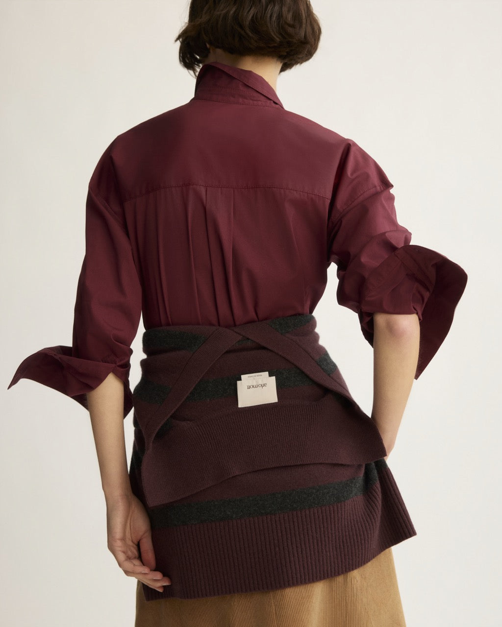 Berry button shirt with bow cuffs and back pleats, styled with striped knit wrap