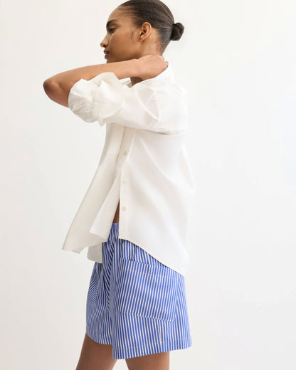 Model wearing white button shirt with side detail, back view on white background