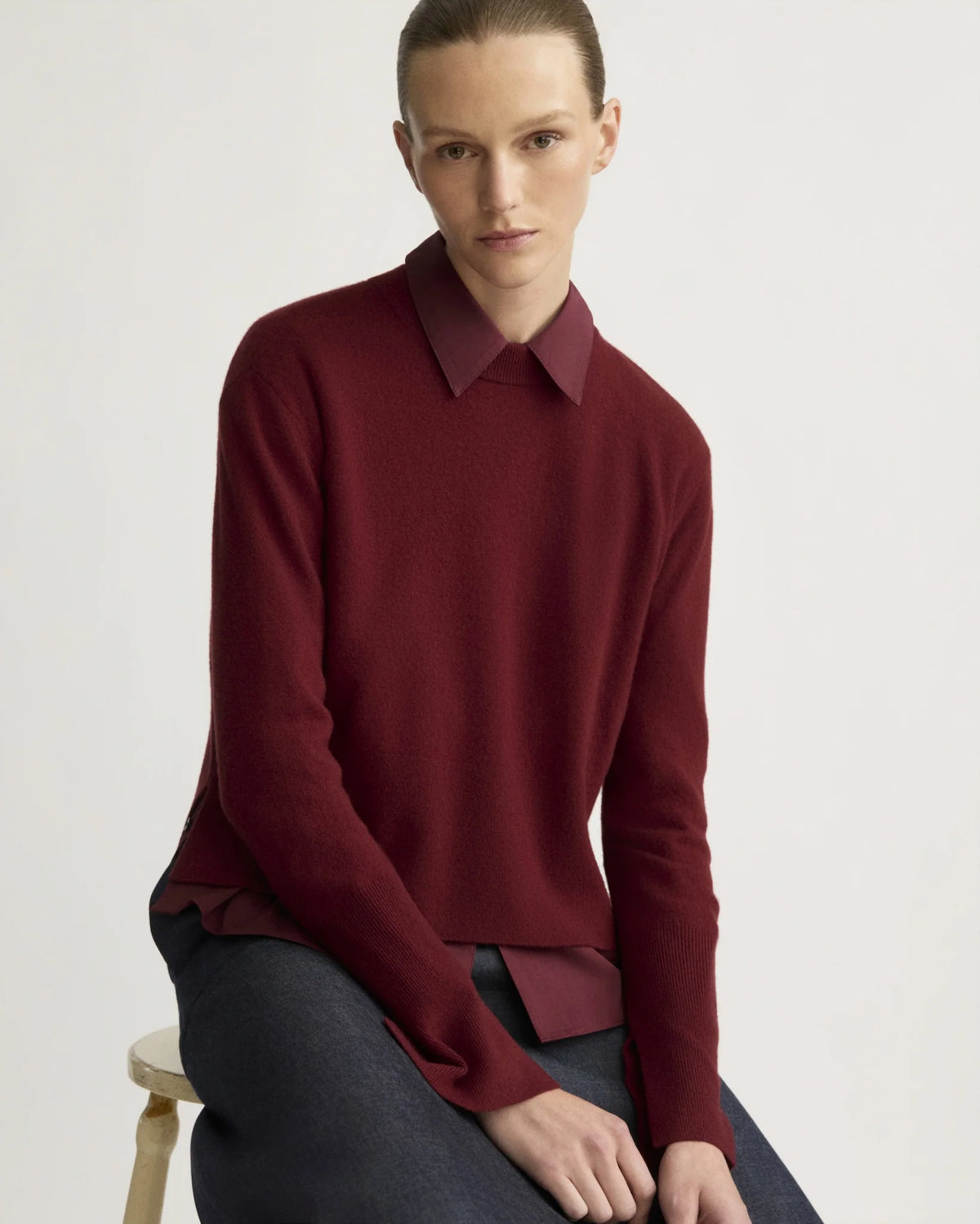 Berry red cashmere crewneck sweater layered over matching collared shirt