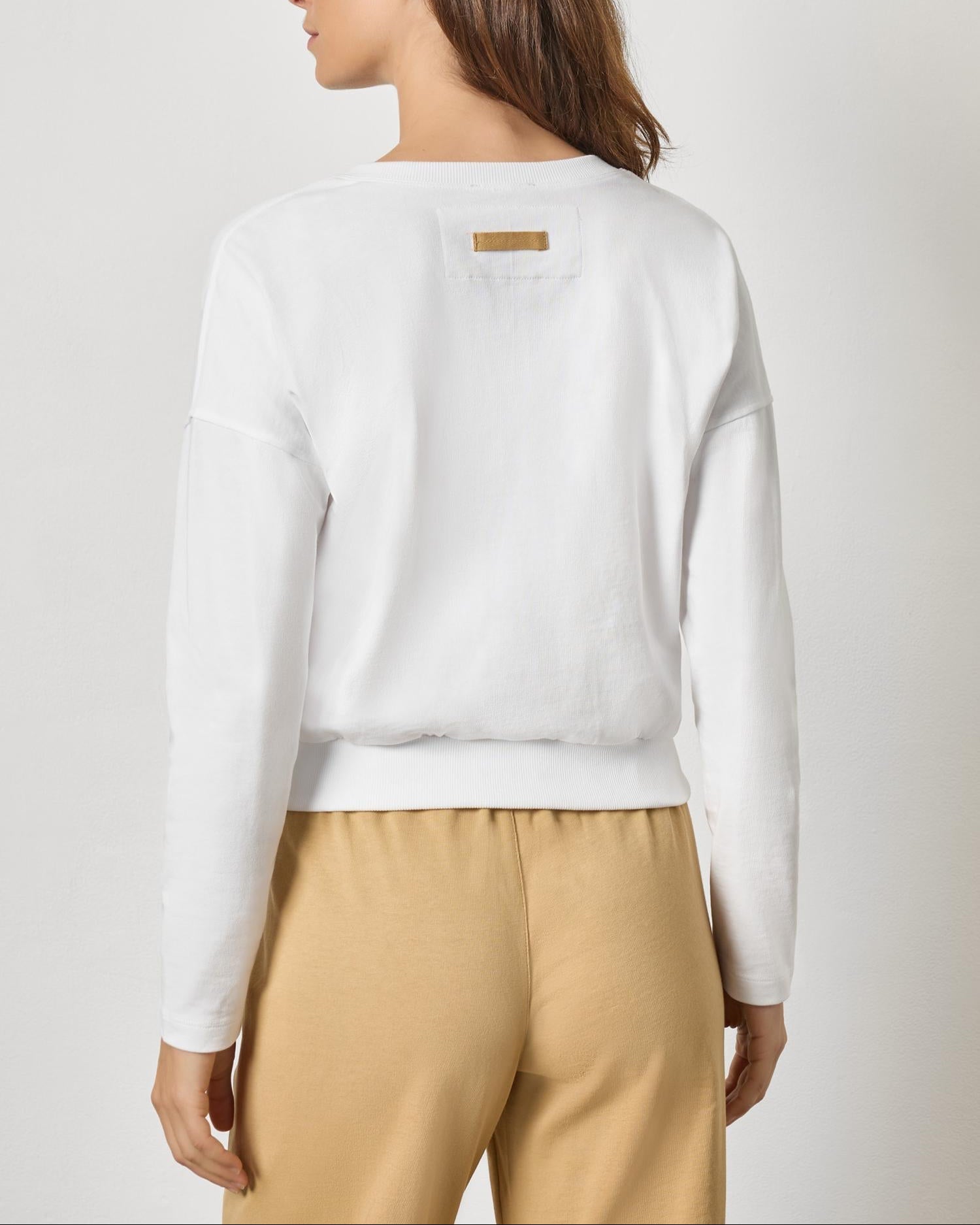 Back view of white rib trim cardigan with gold label detail on model