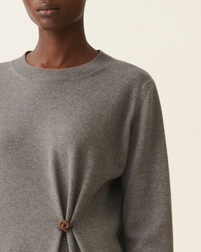 Grey knit long-sleeve dress with gold brooch cinching fabric at front