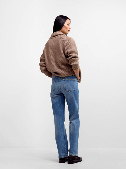 Model wearing brown ribbed knit cardigan with blue jeans, back view