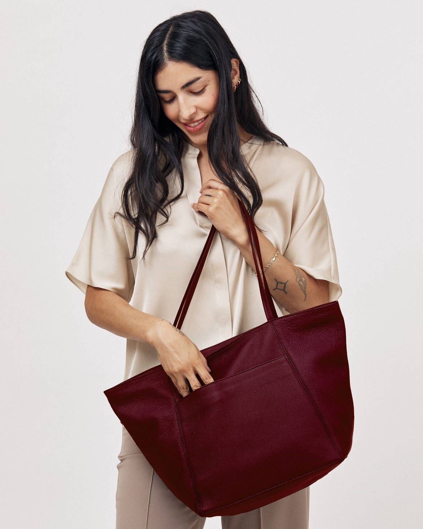Model carrying large plum pebble grain leather Vienna tote bag on shoulder