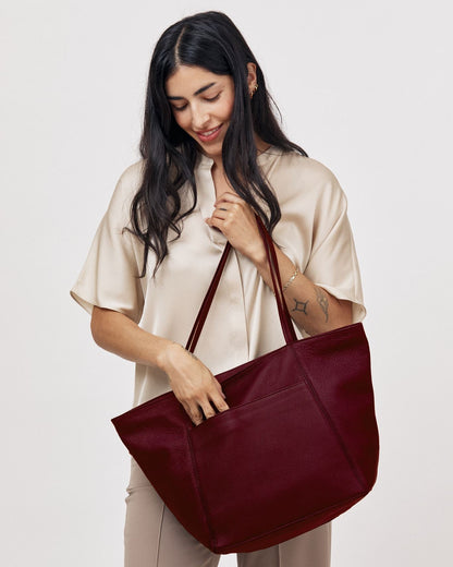 Model carrying large plum pebble grain leather Vienna tote bag on shoulder