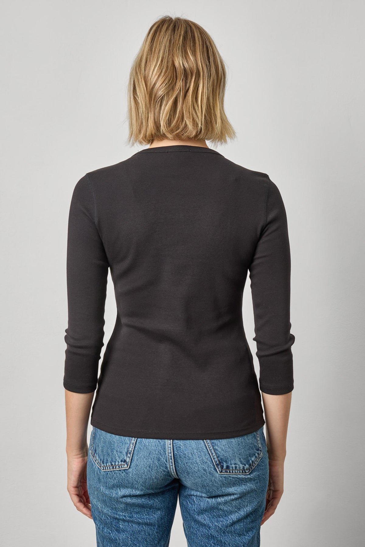 Back view of model wearing Lilla P black 3/4 sleeve crew neck top with blue jeans