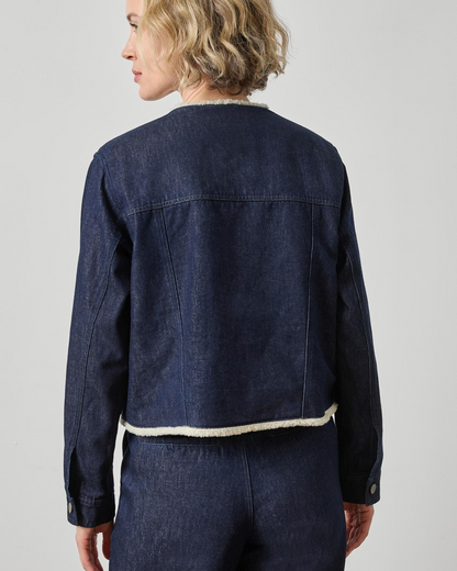 Dark wash blue denim jacket with cream sherpa trim at collar and hem