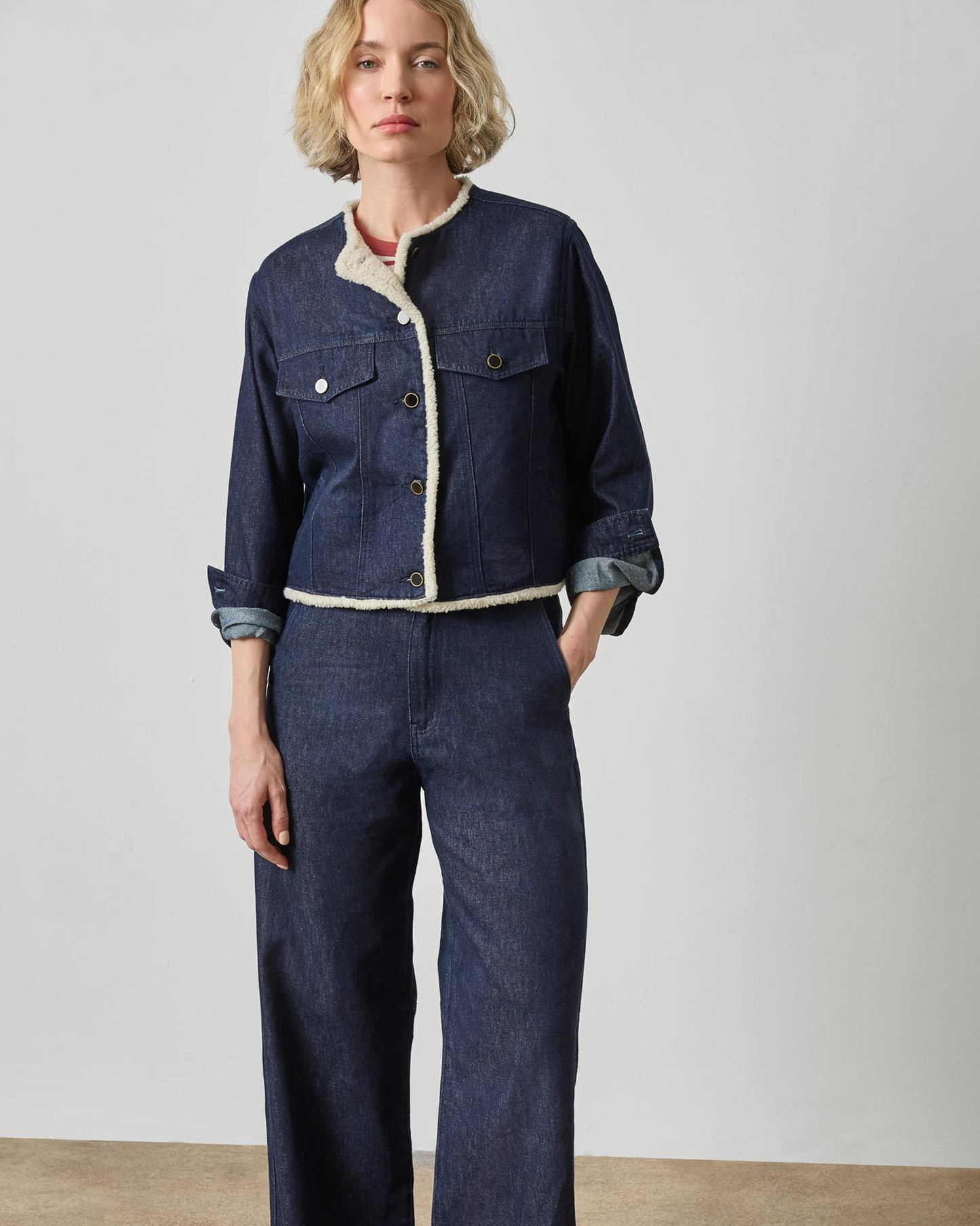 Dark wash blue denim jacket with cream sherpa trim and snap buttons