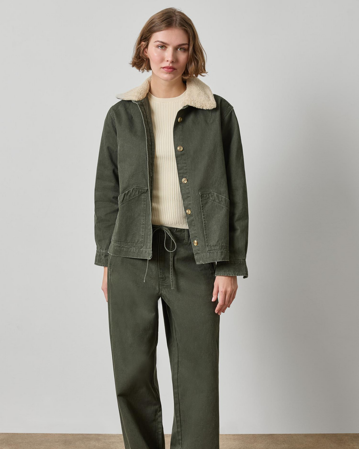 Olive green washed twill jacket with sherpa collar and gold buttons on woman