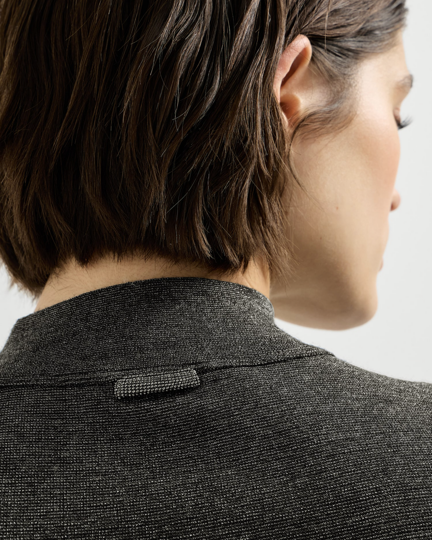 Close-up back view of dark gray sparkle wool rib mockneck with jeweled loop detail