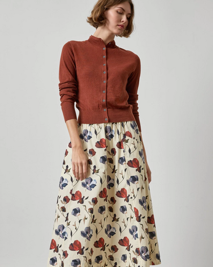 Rust orange funnel neck button-front cardigan with long sleeves, worn over floral skirt.