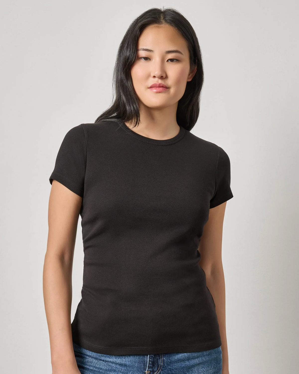 Women's fitted black short sleeve crew neck t-shirt with blue jeans