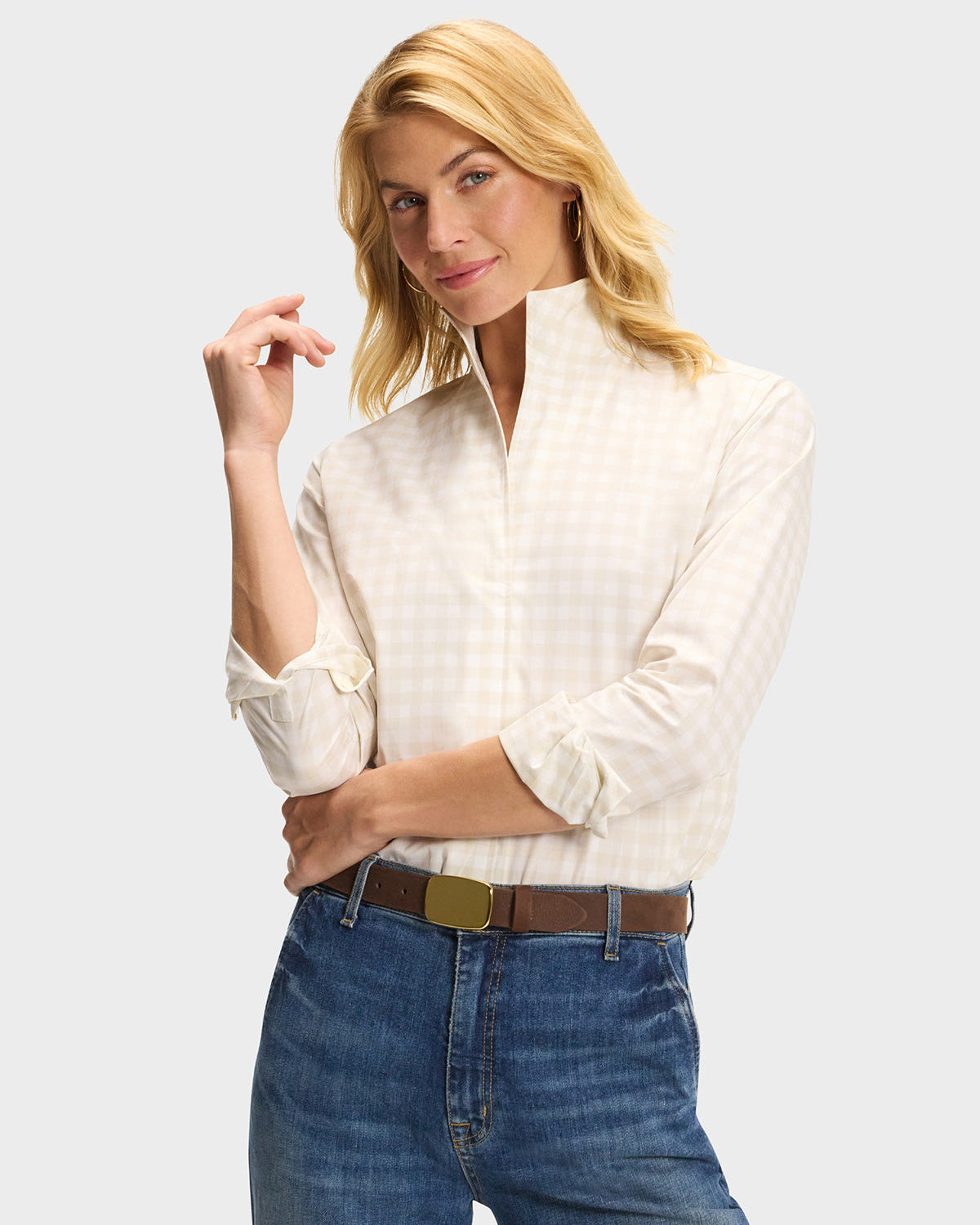 Model wearing cream plaid button-up shirt with rolled sleeves paired with blue jeans and brown belt