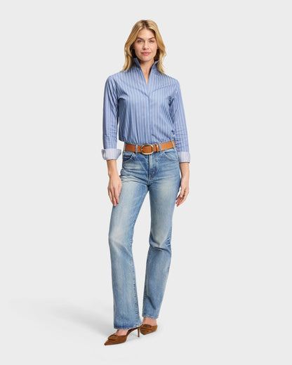 Blue pinstripe Portofino shirt with stand collar, tucked into light wash bootcut jeans