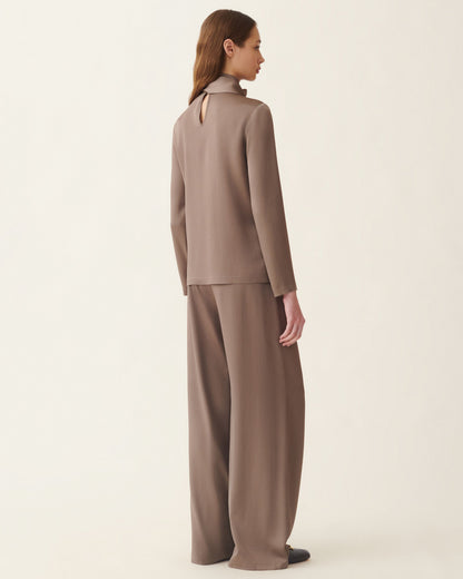 Taupe satin long-sleeve top with open back keyhole detail, worn with wide-leg trousers