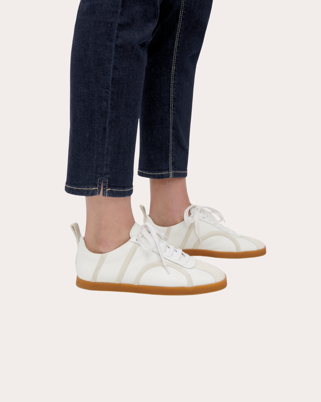 Dark navy cropped straight-leg jeans styled with white lace-up sneakers, gum sole