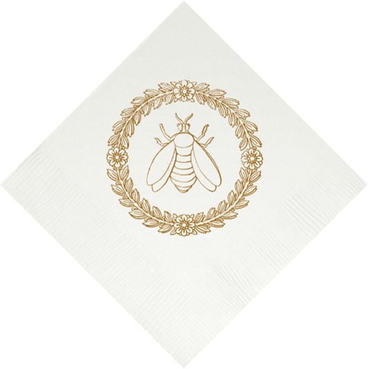 Elegant white beverage napkin featuring gold bee emblem surrounded by decorative wreath