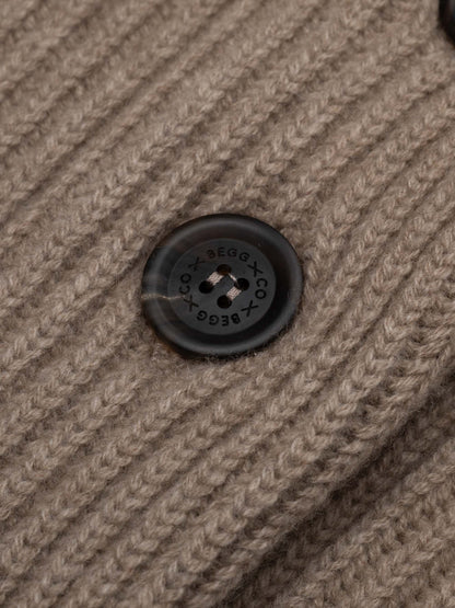 Close-up detail of Begg x Co branded dark button on brown ribbed knit cardigan