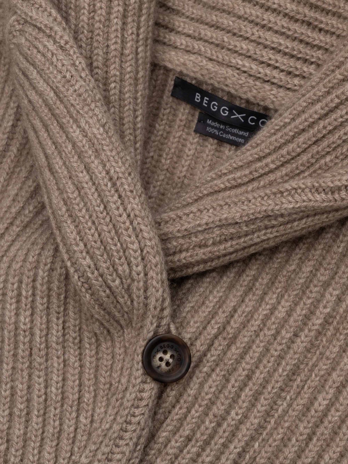 Close-up detail of Begg x Co 100% cashmere ribbed cardigan with shawl collar and branded button