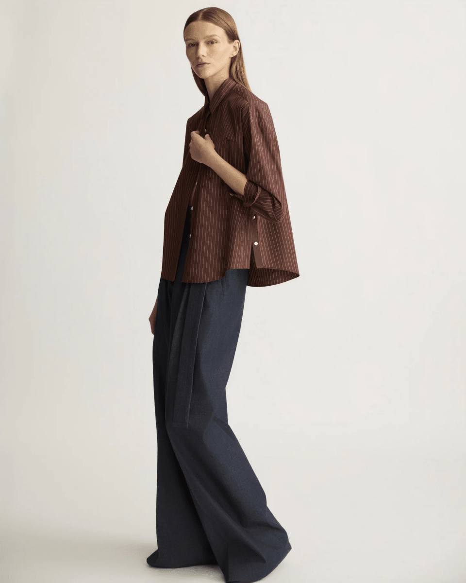 Model wearing oxblood striped side button shirt with wide-leg navy trousers